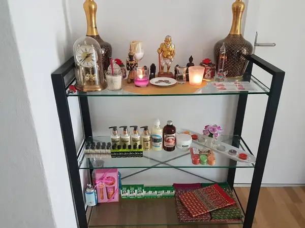 Decorative shelf with candles, statues, massage products, and folded Thai fabrics