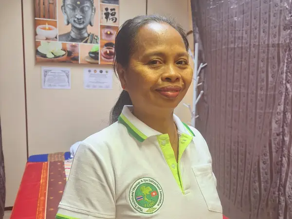 Woman standing in a Thai massage room with wall art and a massage table