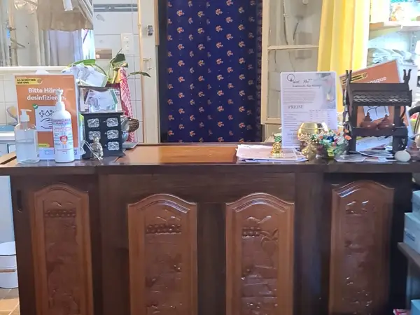 Thai massage reception desk with wooden panels, sanitizer, and floral curtain backdrop