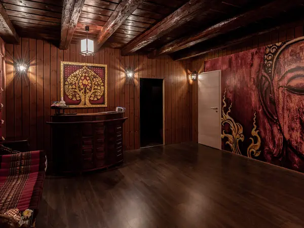 Dim Thai massage reception with wood paneling, wall art, and dark floors