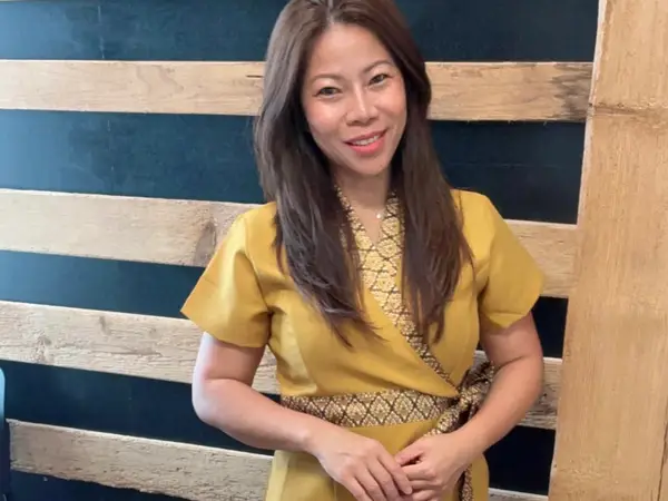 Woman in yellow dress standing before a striped wooden wall
