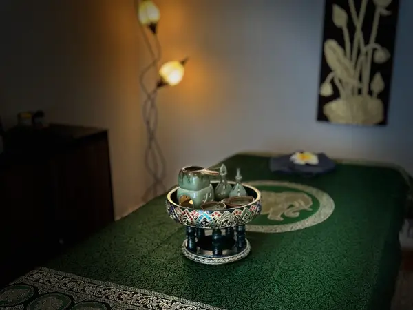 Dim Thai massage room with green treatment bed and decorative tray