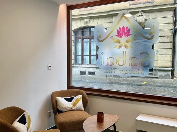 Waiting area with brown chairs, small table, and large storefront window