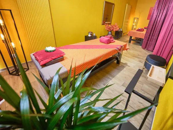Warm Thai massage room with yellow walls, beds, pink towels, and curtains