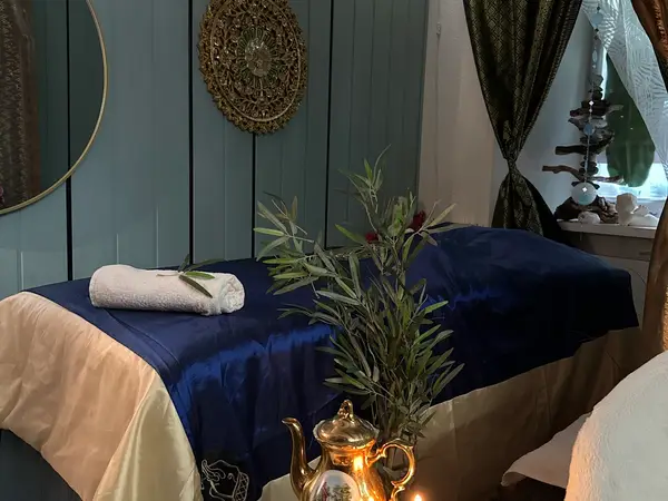 Cozy massage room with blue treatment bed, teal wall, curtains, and decor