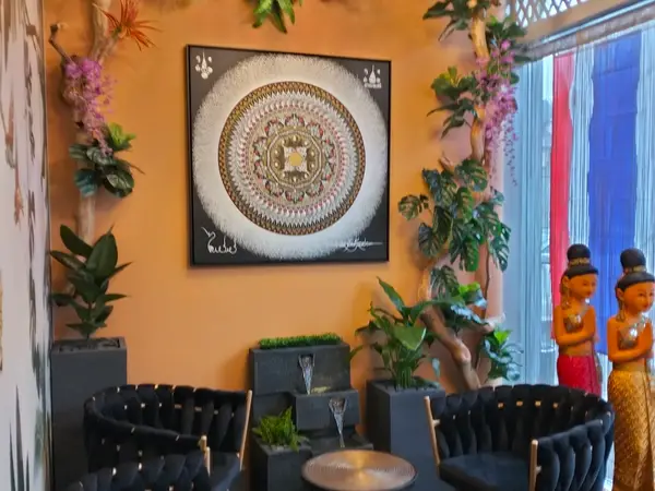 Warm Thai salon seating area with orange walls, plants, and decorative statues