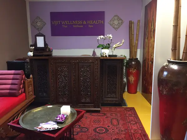 Decorative Thai wellness reception area with carved wooden desk and red rug