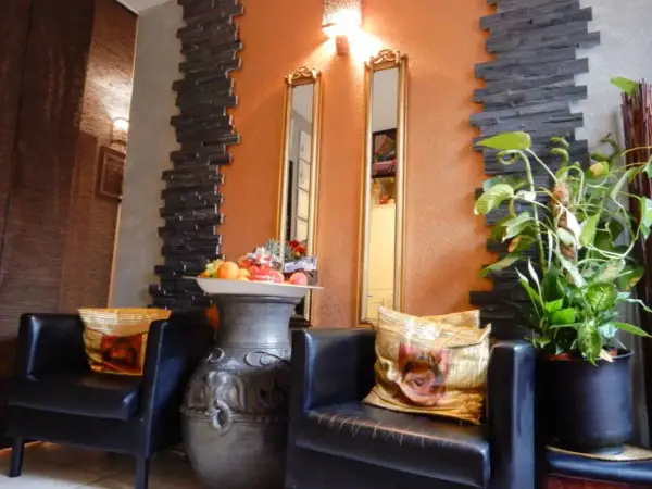 Cozy massage lounge with black chairs, decorative pillows, mirrors, and potted plants