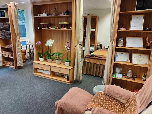Cozy massage room with wooden shelves, curtains, certificates, and treatment beds