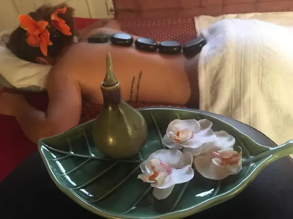 Massage room with hot stones, flowers, and a client on a treatment bed