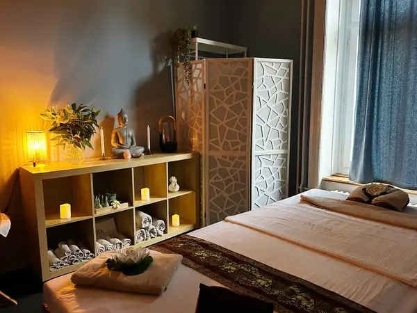 Cozy massage room with bed, candles, Buddha statue, and shelving