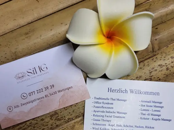 Business cards and a white flower on a wooden surface