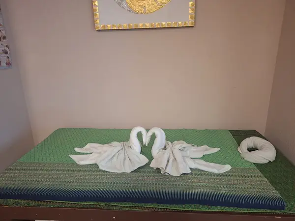 Massage room with green mat, towel swans, and beige walls
