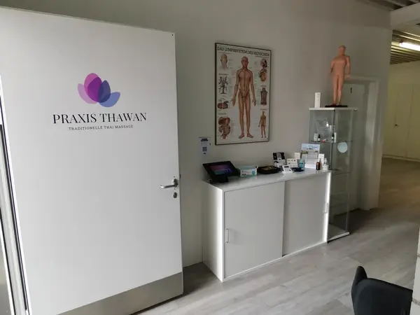 Bright clinic reception with massage logo, anatomy poster, and display cabinet