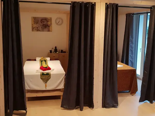 Cozy massage room with curtained treatment beds and Thai decor