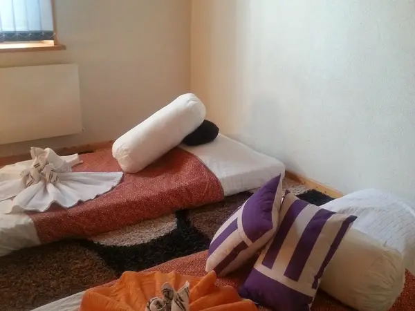 Thai massage room with floor mats, pillows, and folded towels